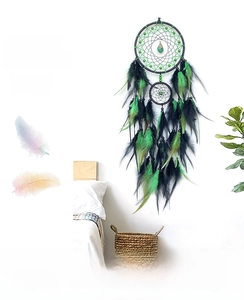 Detail of dream catcher with black woven rings, green beads and natural feathers