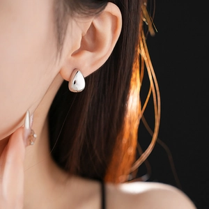 Primo piano di modella che indossa orecchini a goccia in metallo argento dal design sobrio