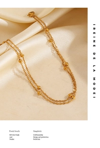 Detailaufnahme einer zweilagigen 18K Gold-Kugelkette auf weichem Seidenstoff