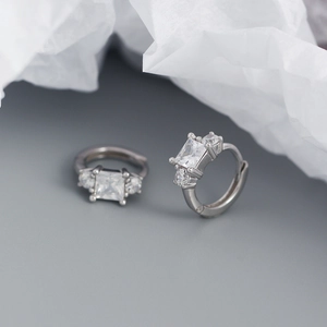 Detailed macro view of silver hoop earrings with square and round cubic zirconia stones