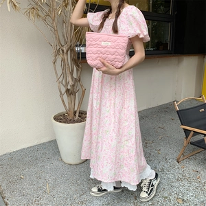 Quilted pink heart clutch bag held by model wearing a floral puff sleeve dress