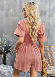 Back view of a pink square neck romper with bubble sleeves and a cinched waist detail