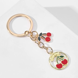 Detail of golden alloy cherry keychain with red enamel fruits and love engraving