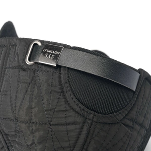 Detail view of quilted black fabric and leather strap with engraved metal buckle on cap