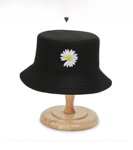 Detailed close-up of white daisy flower embroidery on a black cotton bucket hat