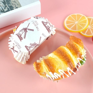 Realistic artificial croissant sandwich and paper-wrapped bread on a pink tray