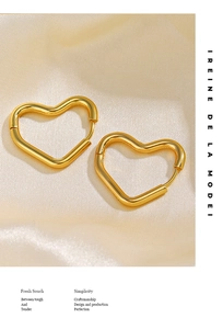 Gros plan détaillé de boucles d'oreilles cœur plaquées or 18 carats sur du tissu de soie beige