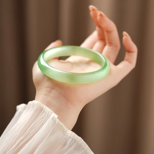 Close-up of light green cat eye stone bracelet showing smooth texture on wrist