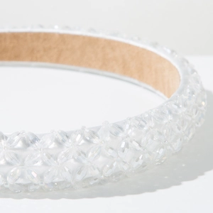 Close-up of woven crystal beads and white satin fabric on a luxury headband