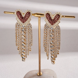 Detail of luxury heart fringe earrings featuring red rhinestones and golden tassels