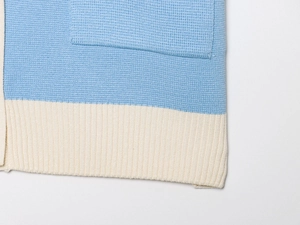 Close-up of sky blue and cream knit shirt hem with detailed ribbing and a large pocket