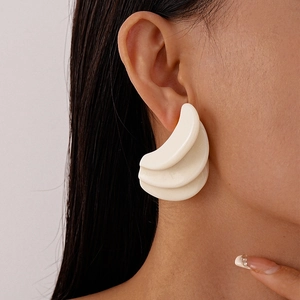 Close-up of a model wearing three-layer resin geometric earrings in creamy white finish