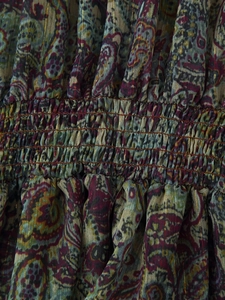 Macro shot of paisley chiffon fabric with gold thread and stretch smocking detail