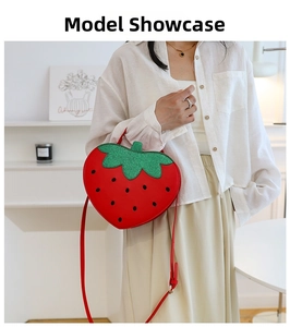 Detail of red strawberry shaped shoulder bag with green leaves and black dot patterns