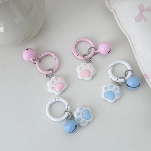 Close-up of pink and blue cat paw keychains with bells and rings on a white desk