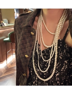 Detail shot of multi-layered long pearl necklace draped elegantly on a female model