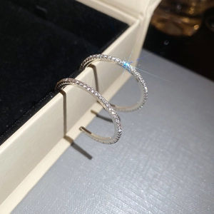 Macro shot of silver C-shaped hoop earrings with sparkling micro-pave crystals on velvet