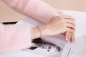 Macro detail of minimalist silver hollow bead bracelet worn on a female wrist
