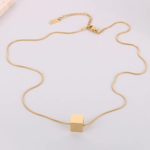 Collier minimaliste avec pendentif cube doré et chaîne serpent sur fond blanc