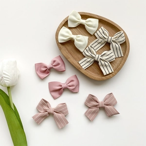 8-piece set of striped and solid color fabric bow hair clips in a wooden tray