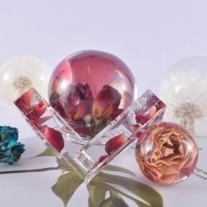 Preserved red rose in clear resin sphere and cuboid on modern base with dried flowers