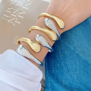 Minimalist teardrop cuff bracelets in gold and silver finish on a female model's wrist