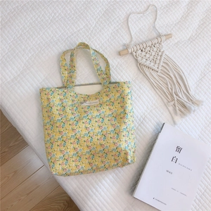 Gros plan d'un sac à main en coton floral avec base jaune et motifs de fleurs roses et bleues