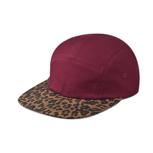 Detalle de gorra de 5 paneles con corona burdeos y visera de leopardo en fondo blanco