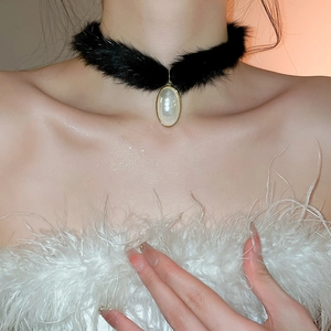 Detailed view of plush black choker necklace with teardrop pearl and golden metal frame