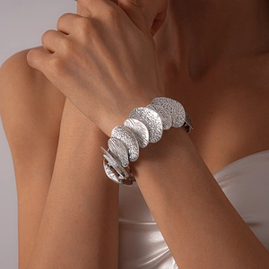 Detailed view of silver irregular textured disc link bracelet on woman wrist