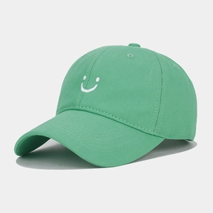 Close-up of green cotton baseball cap with white smiley face embroidery and curved brim