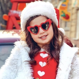 Gros plan d'un enfant portant des lunettes de soleil cœur rouges en décor festif rouge