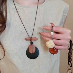 Close-up of ethnic style wooden bead necklace with oval resin shell pendant on beige linen