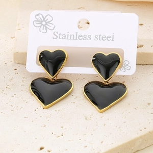 Détail de boucles d'oreilles cœur superposées en émail noir et placage or 18k
