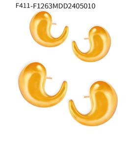 Macro shot of minimalist gold comma-shaped stud earrings in polished stainless steel