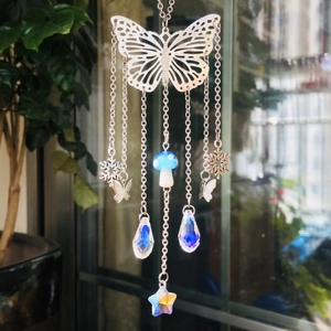 Close-up of butterfly suncatcher with crystal prisms and blue mushroom pendants
