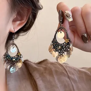 Détail de boucles d'oreilles bohèmes avec perles colorées et pendentifs en coquillage