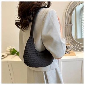 Side view of a black pleated crescent shoulder bag on a model in a modern suit
