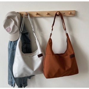 Detail of white and brown crescent hobo bags with adjustable straps and front pocket