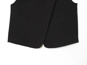 Detail of black double-breasted vest hem featuring overlap split design and woven fabric