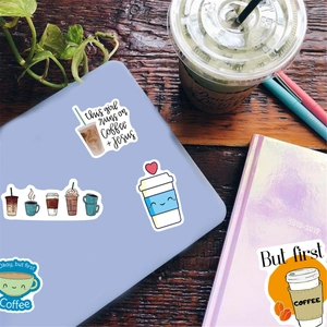 Waterproof coffee stickers set with slogans and cartoon mugs on a wooden desk setup