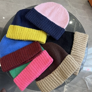 Flat lay of colorful chunky knit beanies in various shades on a modern glass table