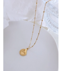 Detailed view of a gold-plated bead chain necklace with a round mermaid tail pendant