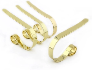 Close-up of four minimalist gold metal Christmas stocking hooks with a polished finish