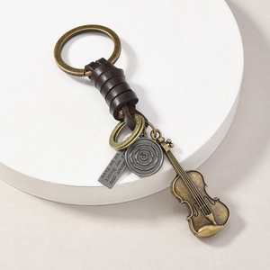 Macro detail of vintage bronze keychain with violin charm and engraved leather strap