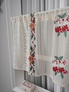 Detailed lace texture with embroidered Christmas socks and bells on a white cafe curtain