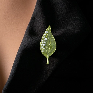 Detail of green leaf brooch with white pearls pinned on a formal black suit lapel
