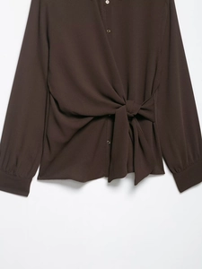 Detail of dark brown long-sleeved shirt featuring a waist tie and woven fabric texture