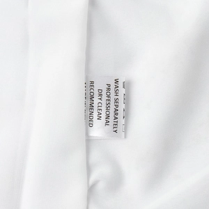 Close-up of washing instructions label on a white floral long sleeve V-neck dress