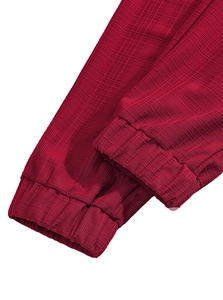 Close-up of dark red textured linen pants with elastic cuffs and woven fabric details